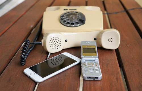 old analog phone, flip phone and a current smart phone